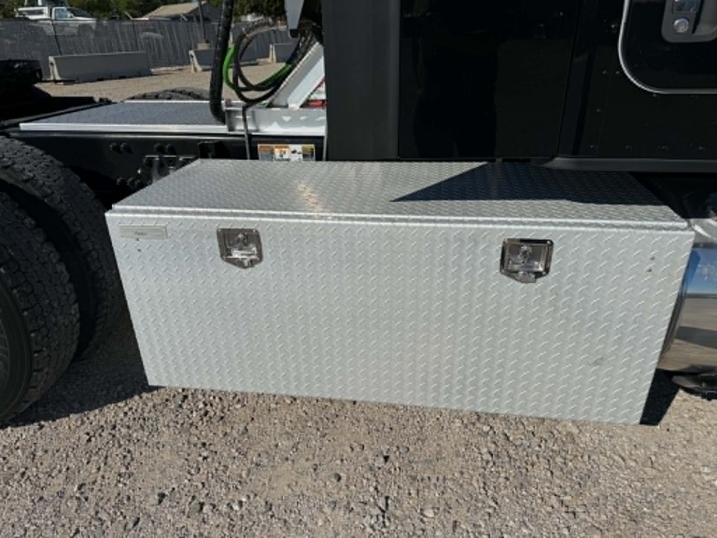 Kenworth T680 side view showing aluminum diamond-plate toolbox mounted under cab with latch handles.