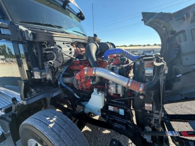 Kenworth T680 engine bay showing red engine, blue and gray hoses, radiator, coolant reservoir, and intake tubing.