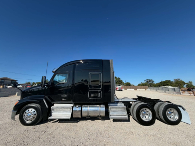 Kenworth T680 conventional sleeper tractor side view showing dual rear axles, black cab, chrome steps and fuel tanks, grille and windows visible