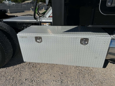 Kenworth T680 side view showing aluminum diamond-plate toolbox mounted under cab with latch handles.