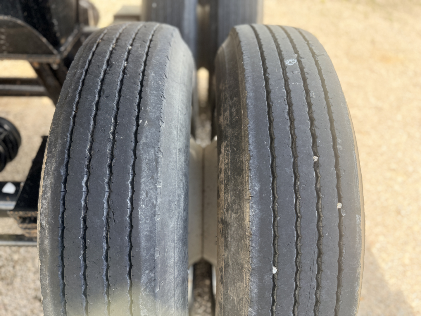 Trailer axle dual tires with tread wear, viewed from above, showing two rear wheels.