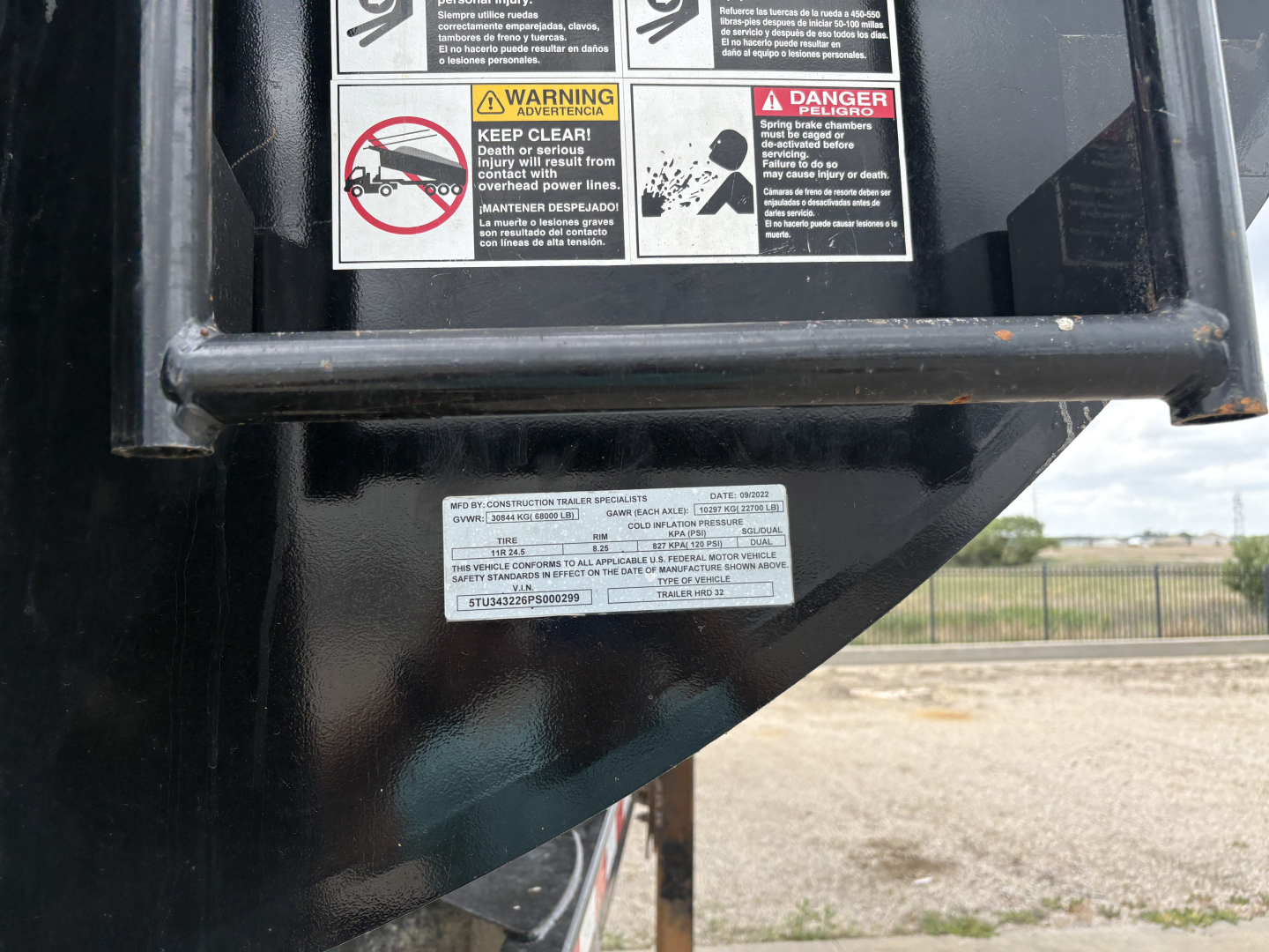 Trailer hitch area showing safety labels and small white sticker with text on the black metal surface.