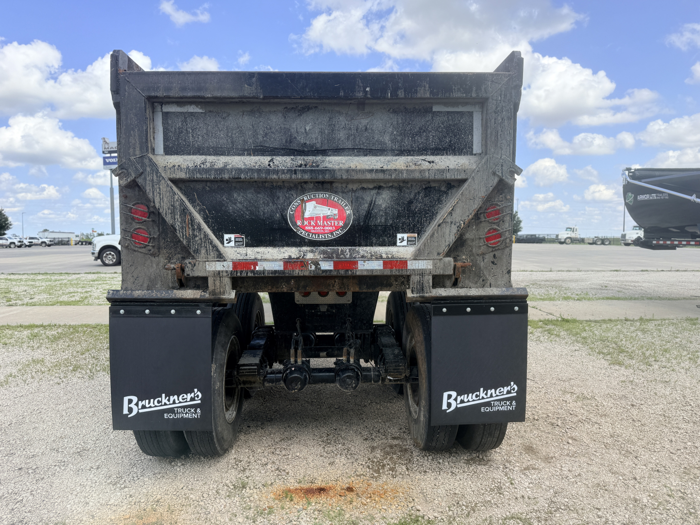 Dump trailer rear view showing dual mud flaps with Bruckner's Equipment logo and trailer hitch assembly