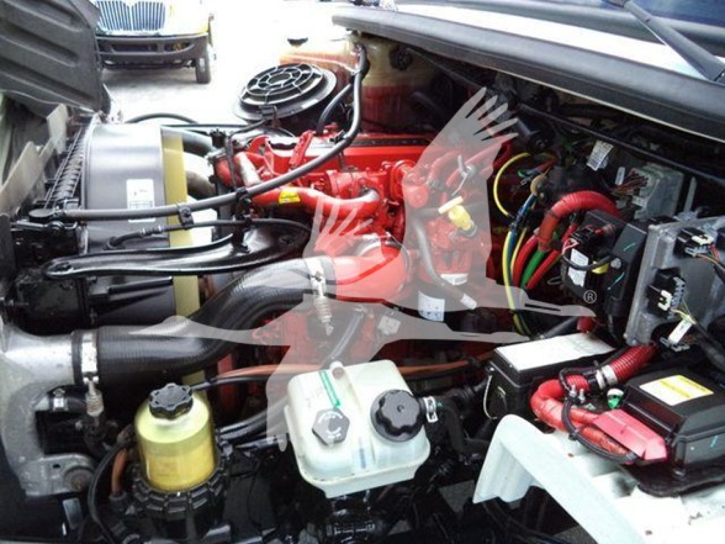 Truck engine bay of a 2019 Freightliner Business Class M2 106 showing coolant reservoir, power steering/auxiliary fluid containers, wiring, and air intake hoses.