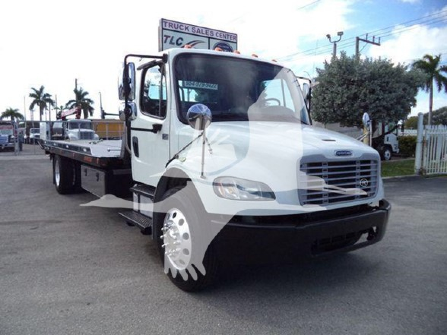 Freightliner Business Class M2 106 rollback truck in white with flatbed, front grille and side mirror visible.