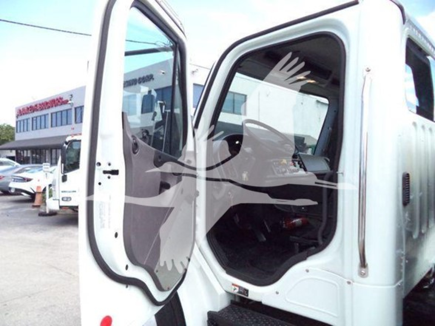 Truck cab interior visible through open door of a Freightliner Business Class M2 106 rollback truck.