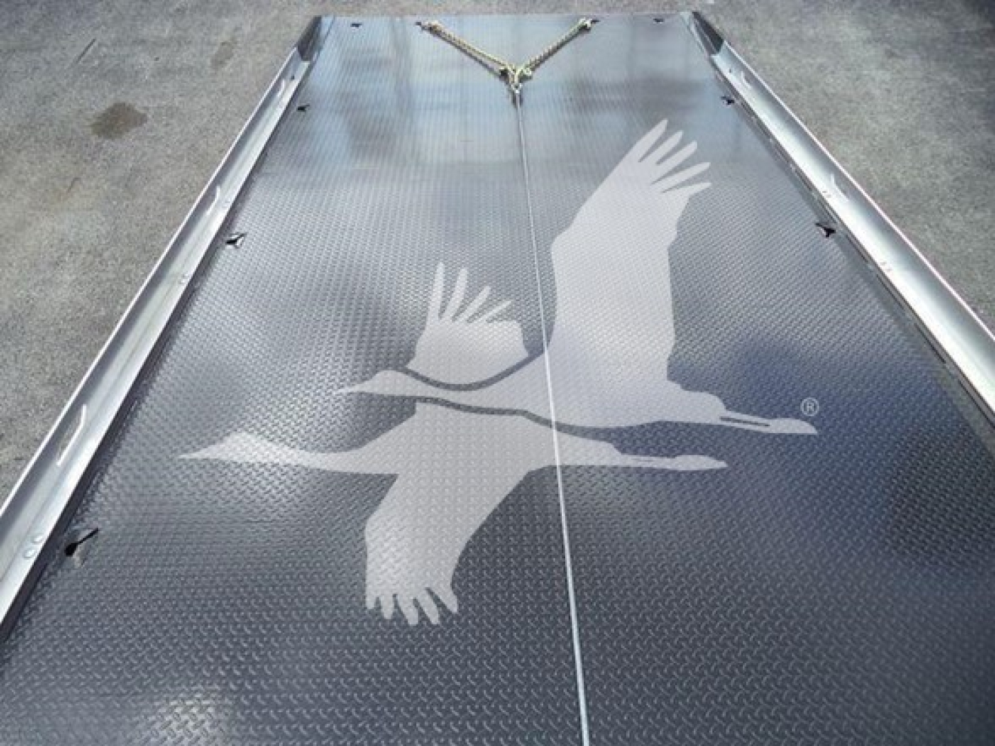 Two-toned metallic rolled platform with diamond plate and a white bird graphic showing on Freightliner Business Class M2 rollback truck bed