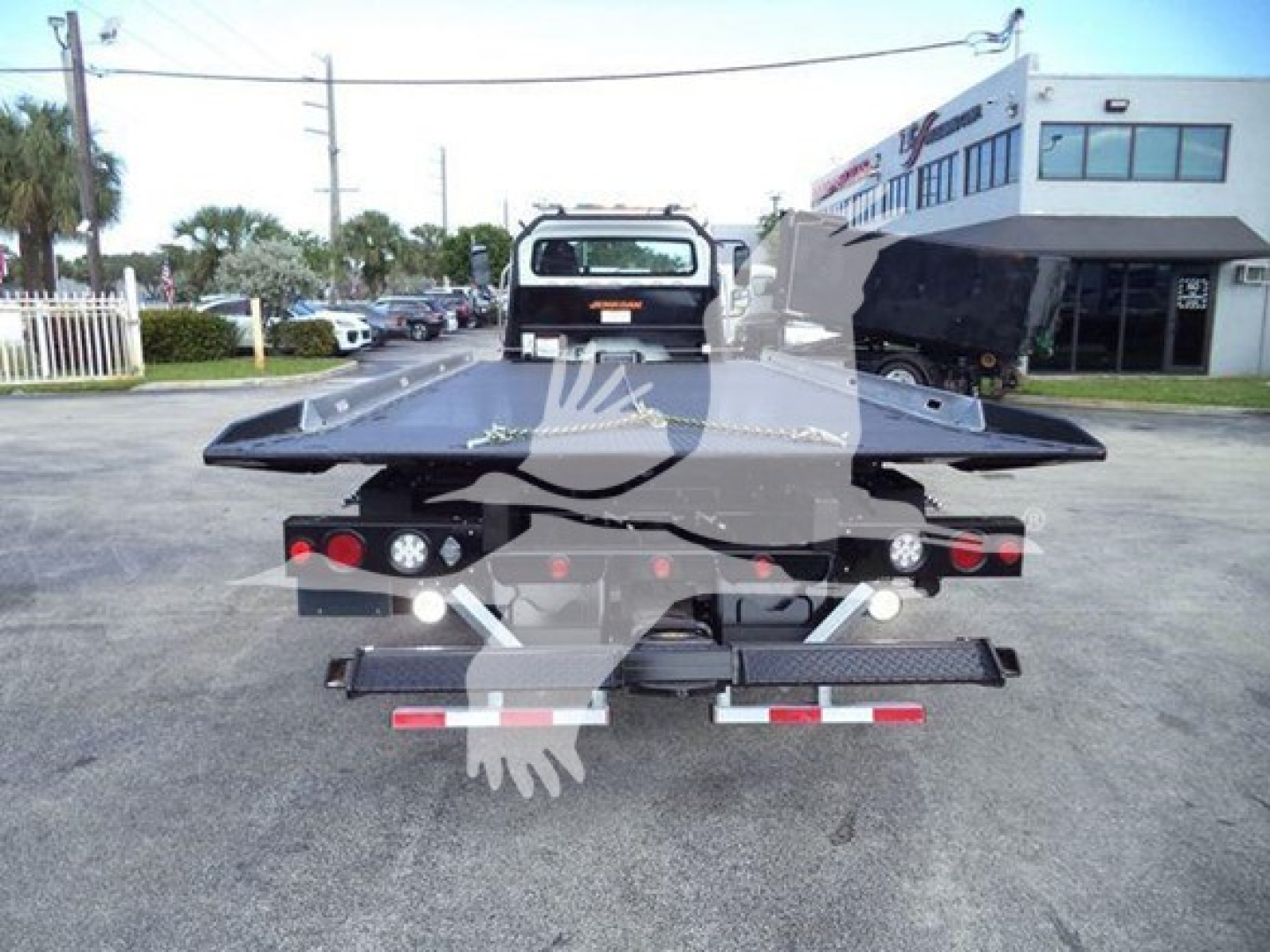 Flatbed tow truck rear view showing platform and taillights on a Freightliner/M2 106 rollback.