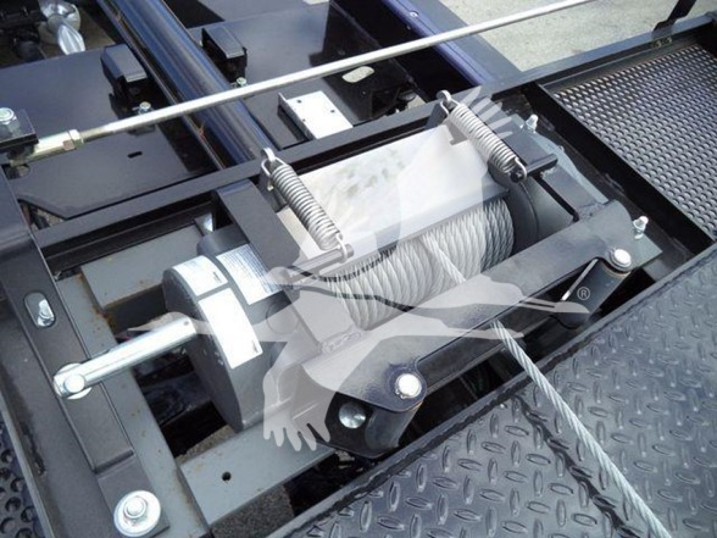 Winch drum and hydraulic line assembly on Freightliner M2 106 rollback chassis showing winch spool and steel cable with drum mounts.