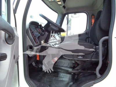 Cab interior of a Freightliner Business Class M2 106 truck showing driver seat, steering wheel, dashboard, and pedals.
