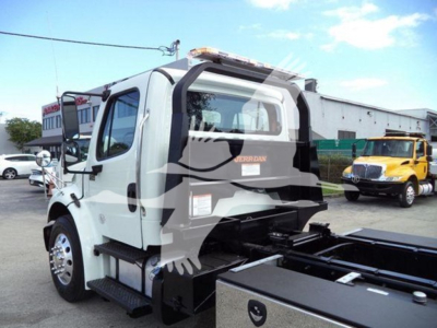Freightliner Business Class M2 106 rear view showing utility bed and rollback setup; cabin window, rear ladder, and side steps visible.