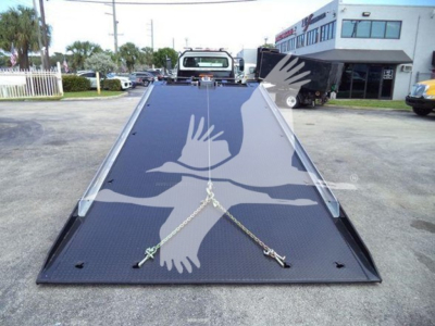 Truck bed with hydraulic rollback tilt showing welded metal surface and chain anchors on a Freightliner rollback truck bed.