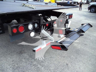 Freightliner Business Class M2 106 rollback truck rear showing hydraulic lines, taillights, and fold-out ramp in the concrete yard.