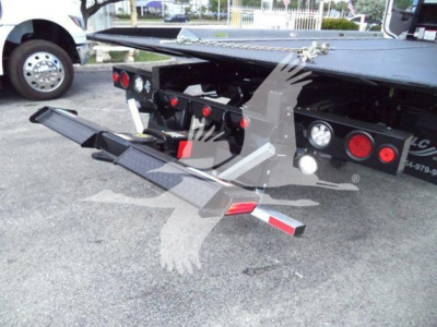 Back view of a Freightliner rollback truck with a lowered hydraulic tow bed and platform, hydraulic ramps folded out.
