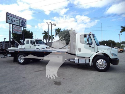 Truck with a flatbed car carrier in a parking lot showing Freightliner Business Class M2 106 style cab; no readable labels or serials on the visible surface.