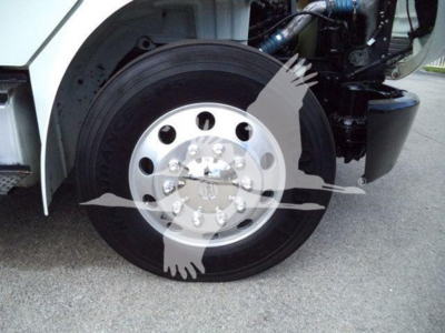 Truck front wheel well showing chrome wheel with multiple lug nuts and part of black tire; part of white truck body and engine components visible.