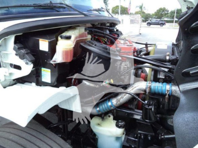 Freightliner M2 106 engine bay showing coolant reservoir and various hoses and components.