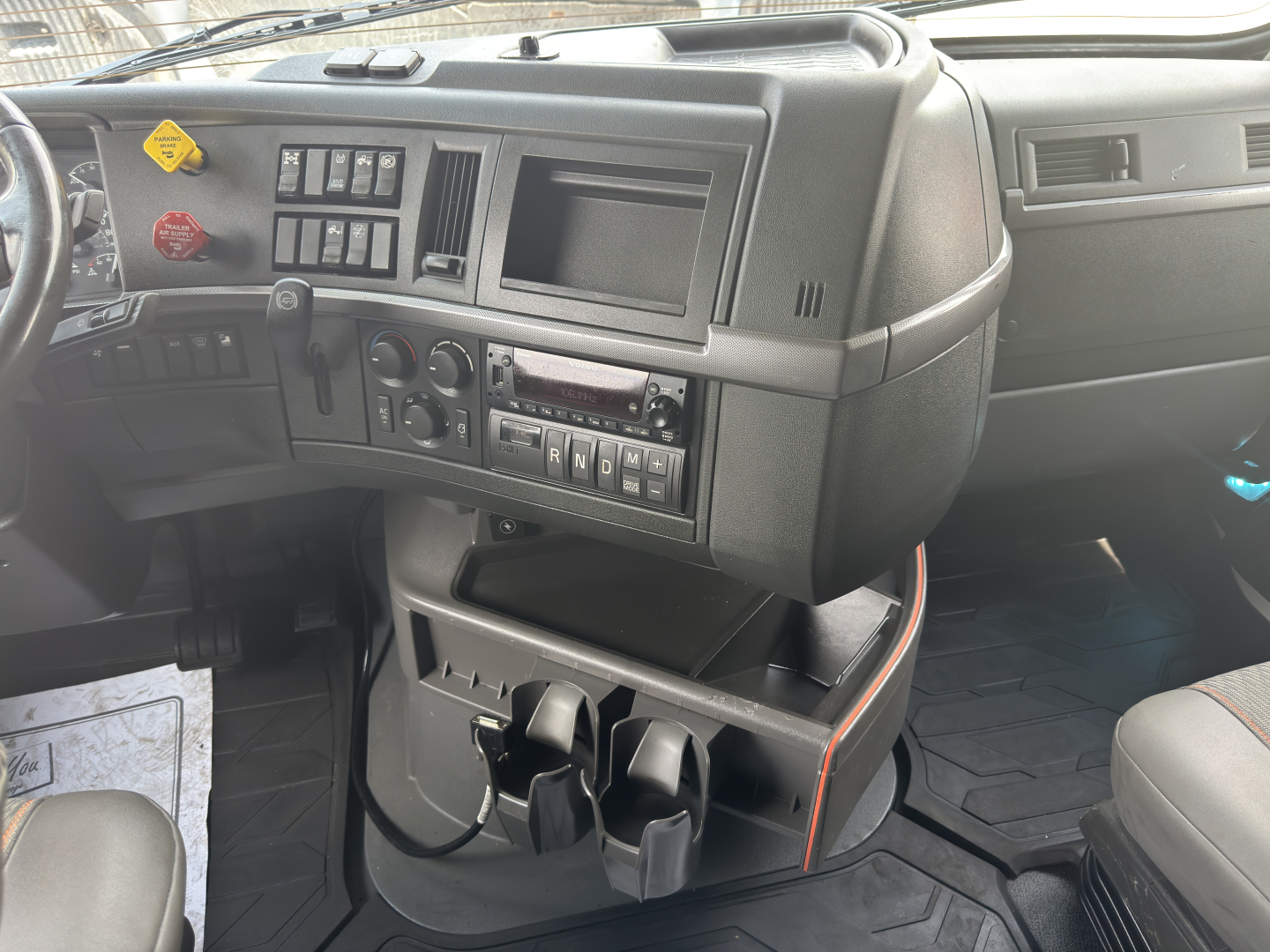 Volvo VNL64T760 cab interior showing dashboard controls with multiple switches, vents, and cup holders