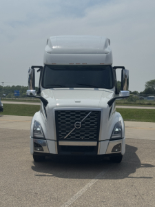 Front view of a white Volvo VNL truck with large grille, bumper, and mirrors. No text clearly legible on the vehicle surfaces.