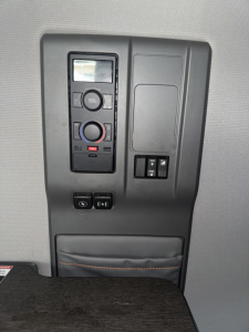 Inside cab overhead controls panel with circular climate dial, display screen, and switches in a Volvo VNL interior
