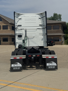 Rear view of a Volvo VNL truck sleeper showing white cab back, rear fenders, mud flaps with Kordell decals, and wiring harnesses under the raised cab.