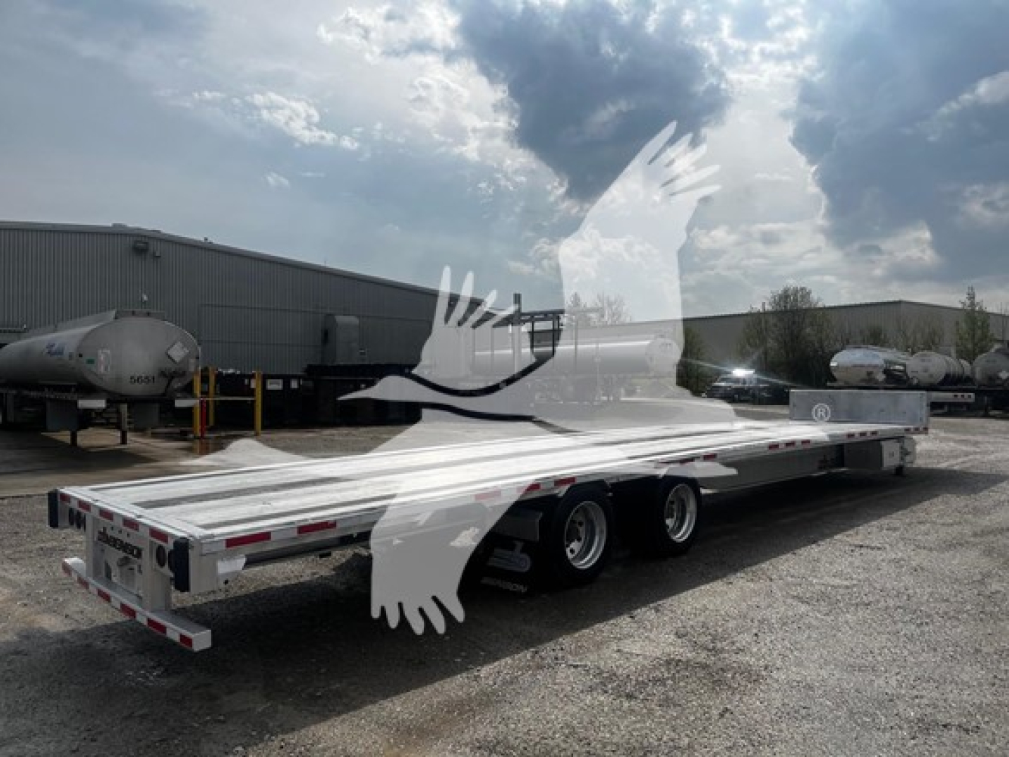 Transcraft aluminum drop deck trailer in yard, side view, three axles, reflective tape along sides, VIN 1TTE532A2P3350354 on listing