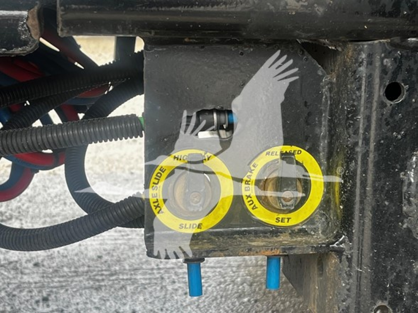 Trailer hitch area showing yellow circular safety latches labeled 'NEW BRAKE SLIDE' and 'BRAKE RELIEF SET' with blue pins and wiring harnesses.