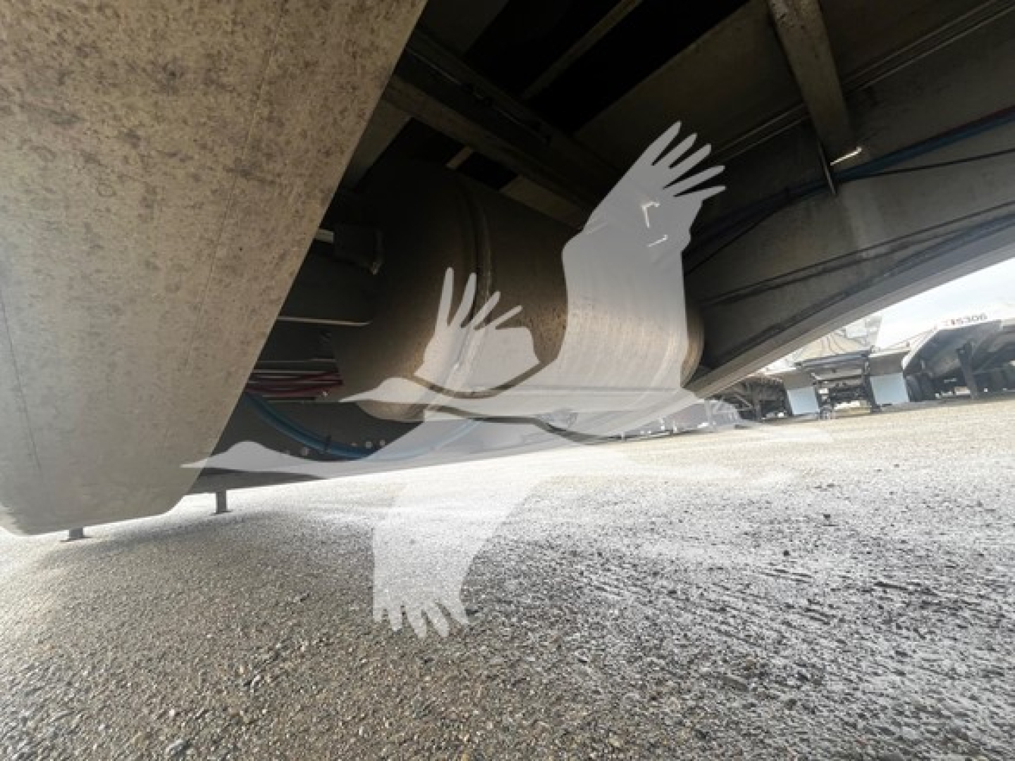 Trailer underside view showing aluminum drop deck with reflection of two birds overlay image.