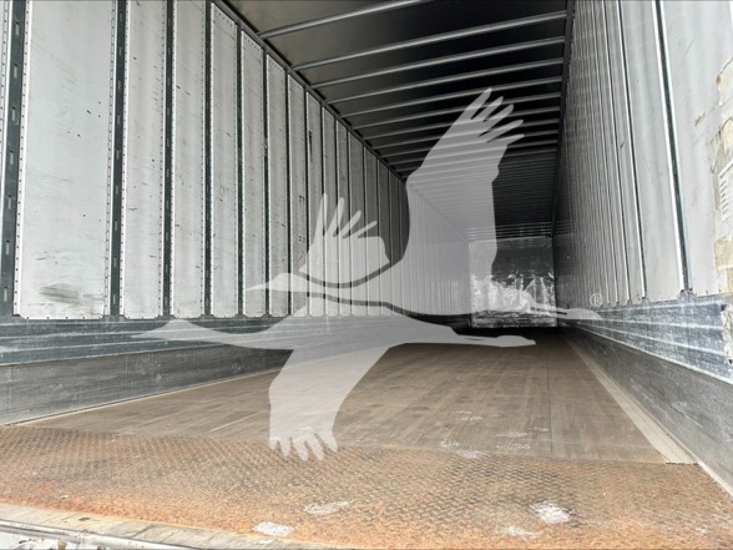 Inside a utility trailer with wooden floor and metal sidewalls; empty cargo area visible.