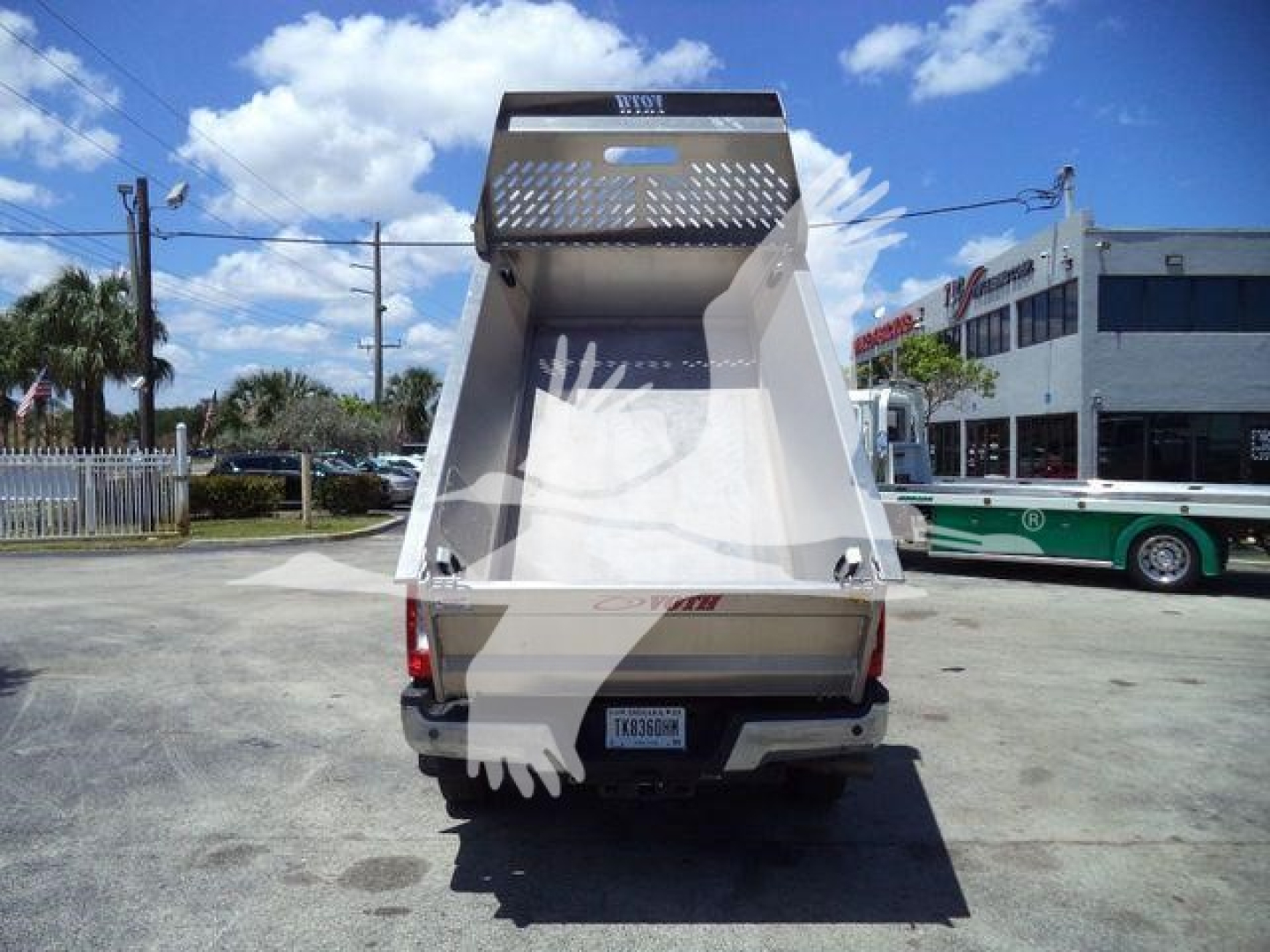 Rear view of a Volvo aluminum dump truck bed, with tailgate and interior, showing a back window and metal lattice guard on top.