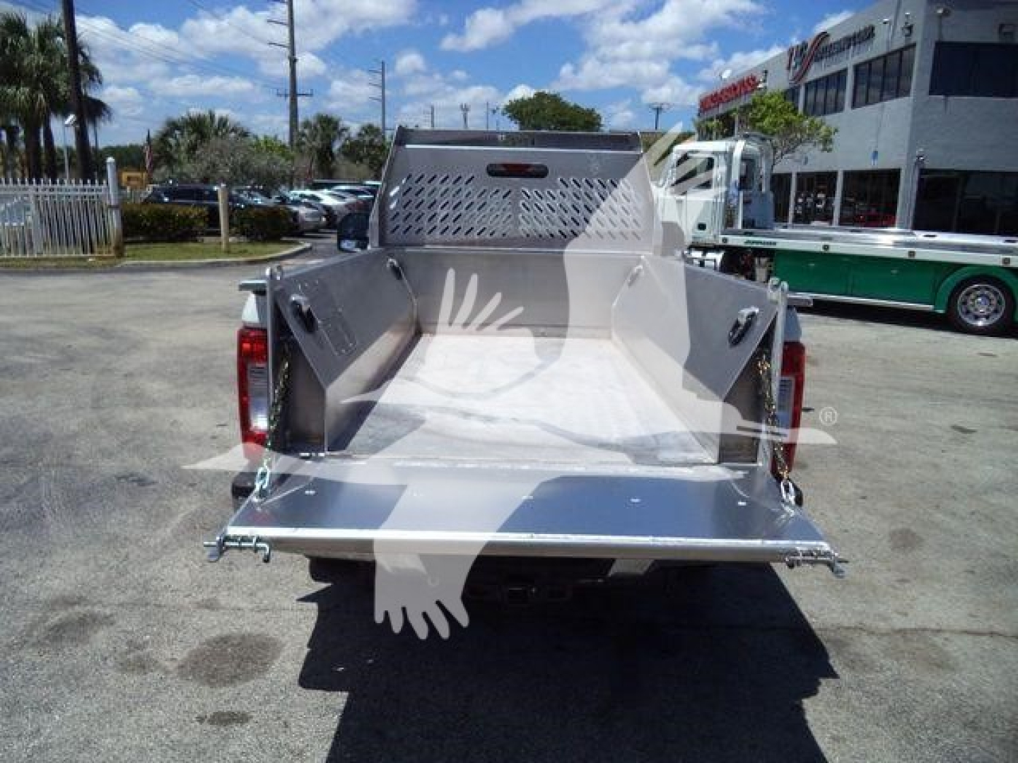 Rear view of a new Volvo 8 ft truck bed with aluminum sides and a drop-down tailgate, visible in a dealership lot.