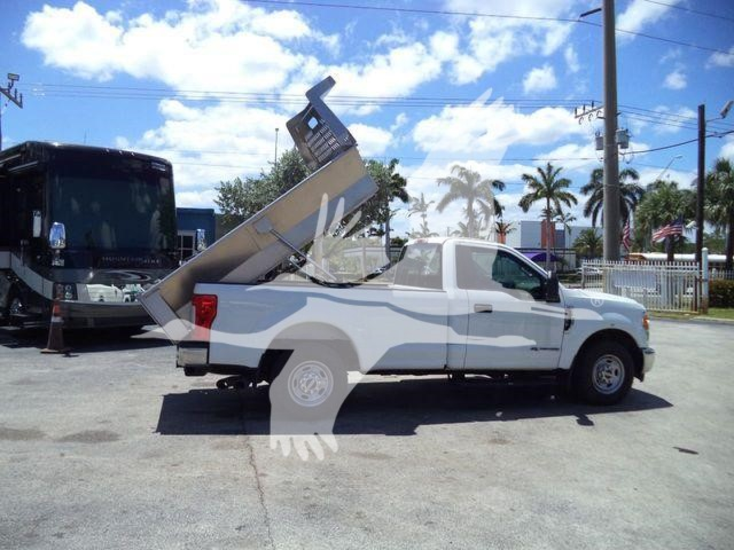 Truck bed dump in raised position on white Volvo 8 ft utility truck viewed from side