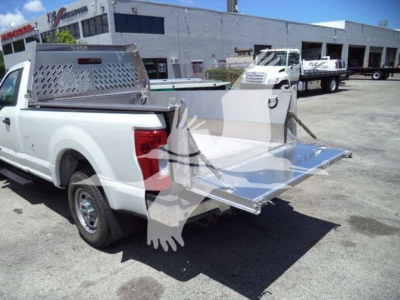 Truck bed with aluminum utility body, fold-out tailgate/steps and perforated tool box in rear view showing aluminum hauler housing and loading platform.