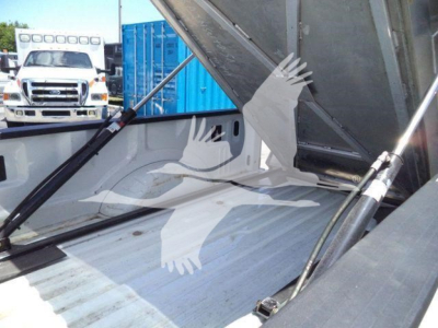 Volvo truck bed showing hydraulic lift and aluminum stake truck with tailgate in a loading area.