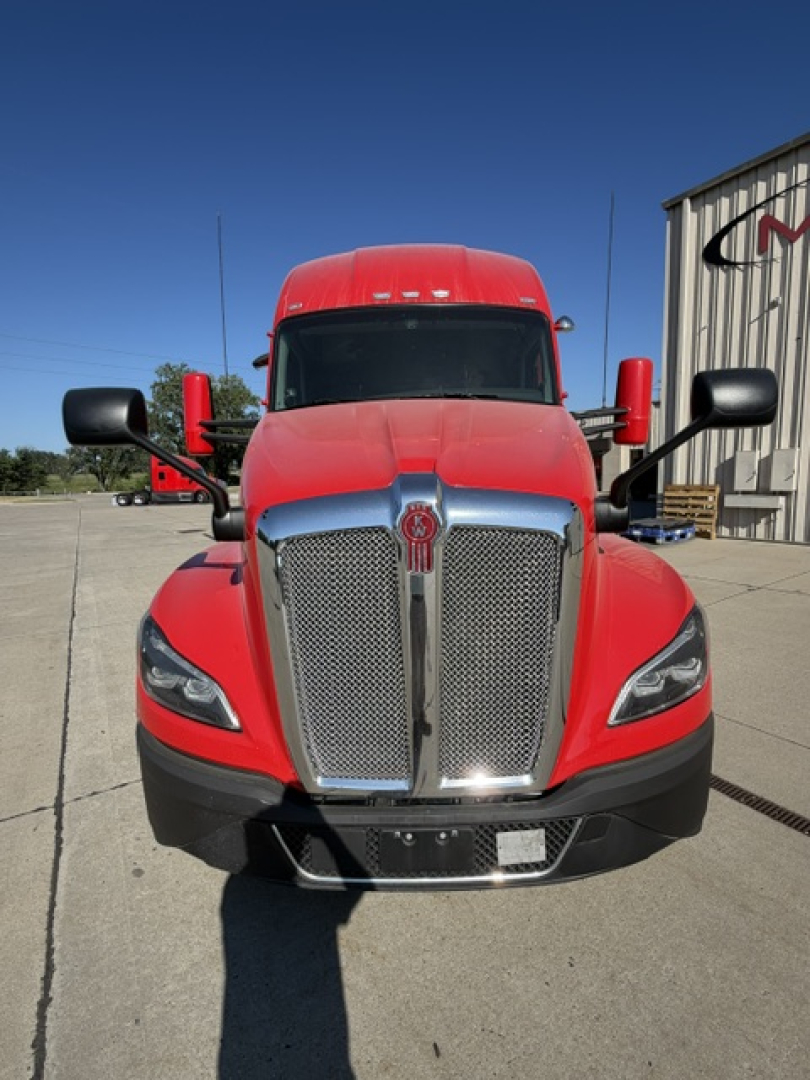 Kenworth T680 head-on view showing bold chrome grille and red cab with black bumper and mirrors.
