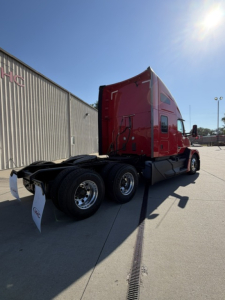 Kenworth T680 tractor shown from rear three-quarter view, red cab, dual rear axle, fifth wheel and chassis visible.