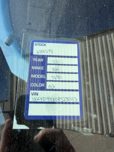 Stock label on Kenworth truck window showing details: STOCK 0629278, YEAR 23, MAKE KW, MODEL T680, COLOR RED, VIN 1XKYD49X0PJ230113