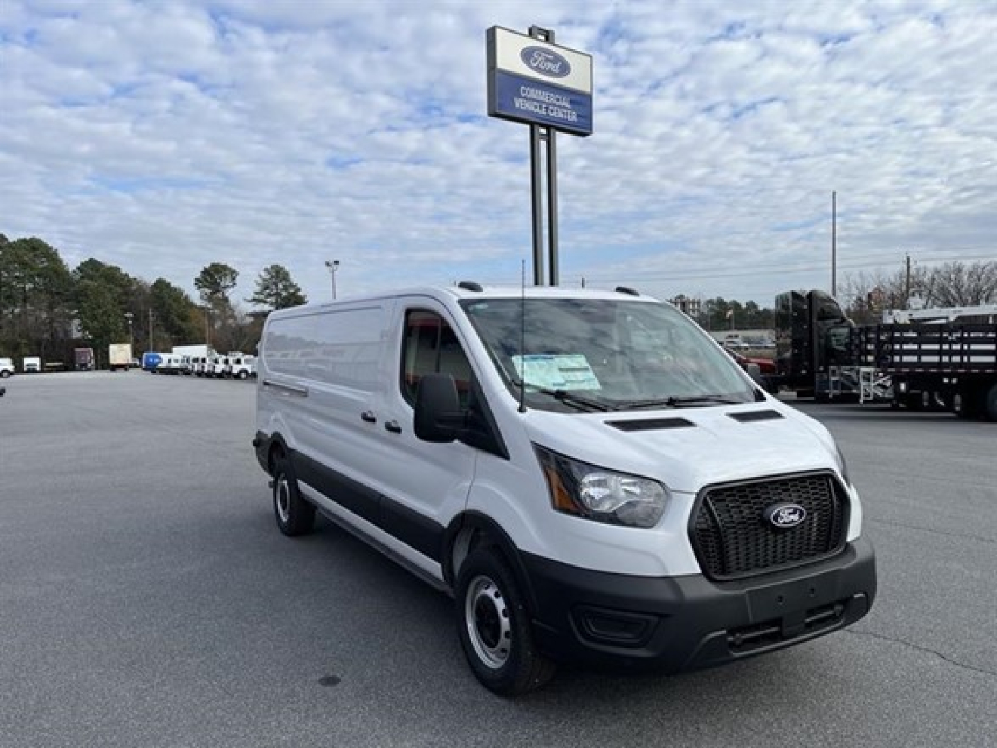 Ford Transit cargo van in dealership lot showing front-right view with open cargo area, grille, and Ford badge.