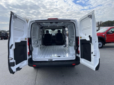 Ford Transit cargo van rear view with doors open showing empty cargo area and two rows of seating in front.