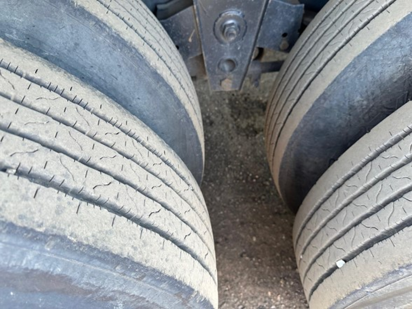 View of trailer tandem wheels on a Direct Steel flatbed showing tire treads and chassis nearby.
