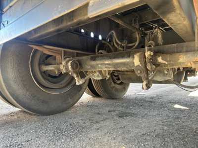 Direct Steel 2012 flatbed trailer undercarriage showing dual rear axles, leaf spring suspension, and drivetrain/driveline components.