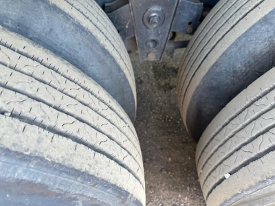 Dual rear tires of a flatbed trailer showing tread details and wear marks.