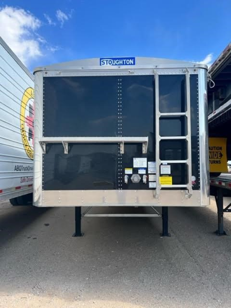 Stoughton hopper trailer rear view showing Stoughton logo plate and loading door with ladder on right side.