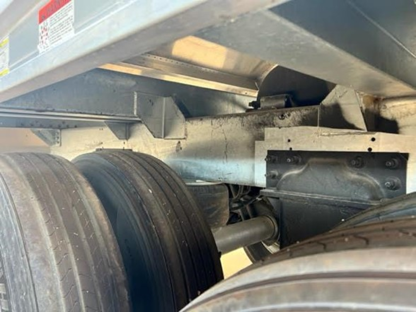 Trailer undercarriage view showing dual rear axles and suspension with metal frame and components of a hopper trailer.