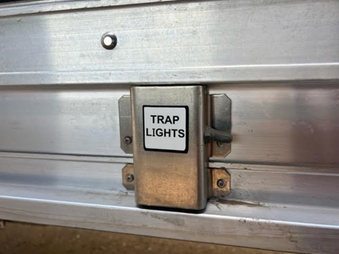 Trailers showing a metal electrical junction box labeled TRAP LIGHTS mounted on the side panel of a Stoughton hopper trailer.