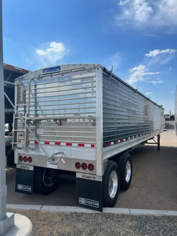 Stoughton Ag hopper trailer in side/rear angle showing aluminum panels, rear gate, taillights, and dual axles with Stoughton mudflaps.