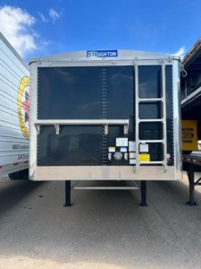Stoughton hopper trailer rear view showing access ladder on right and blue Stoughton label at top center.