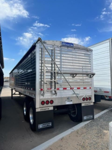 Stoughton Ag hopper trailer rear view showing metal slat sides, rear ladder, taillights, and Stoughton branding.