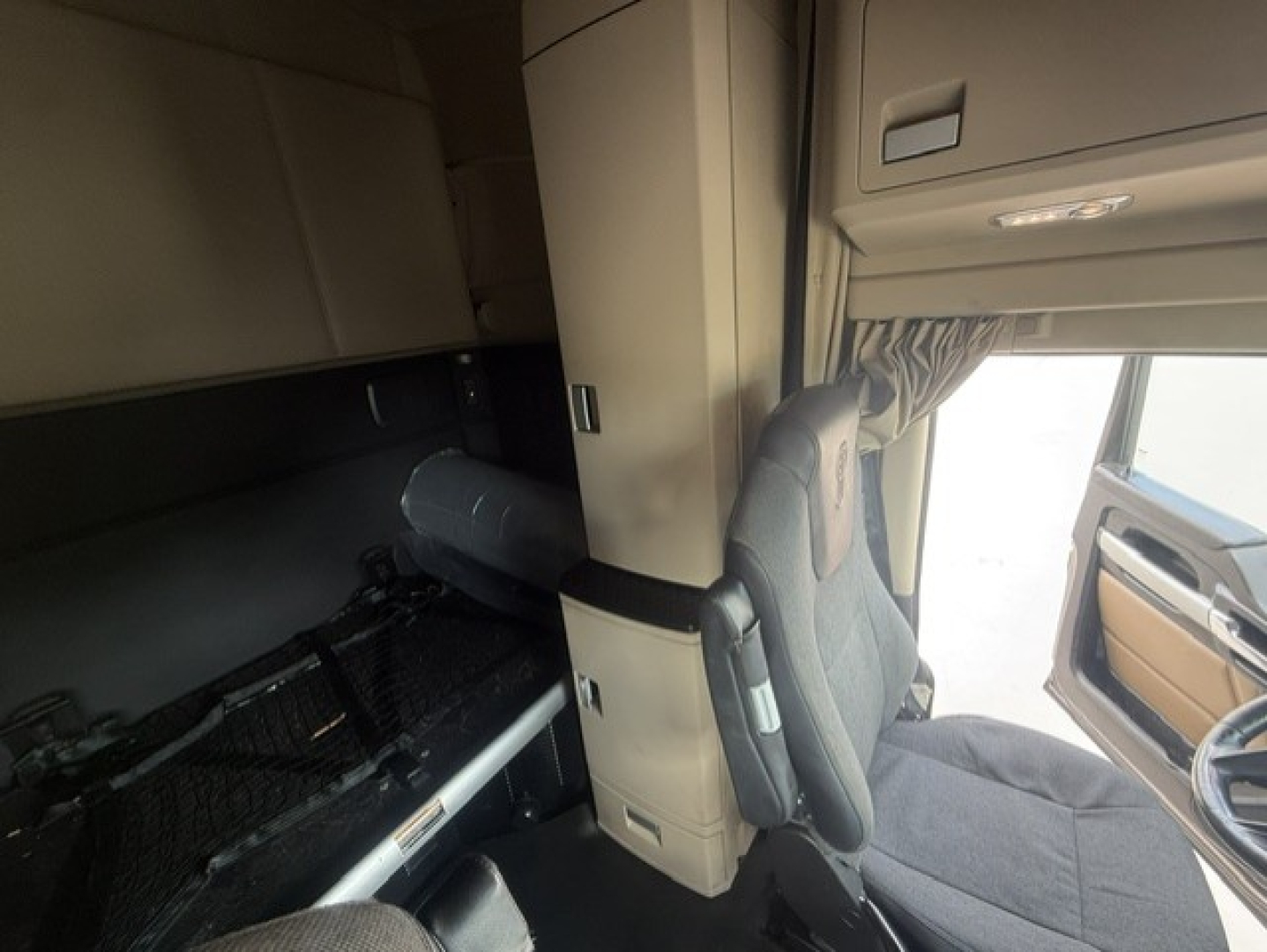 Kenworth T680 cab interior showing sleeper area and driver's seat with overhead compartments.