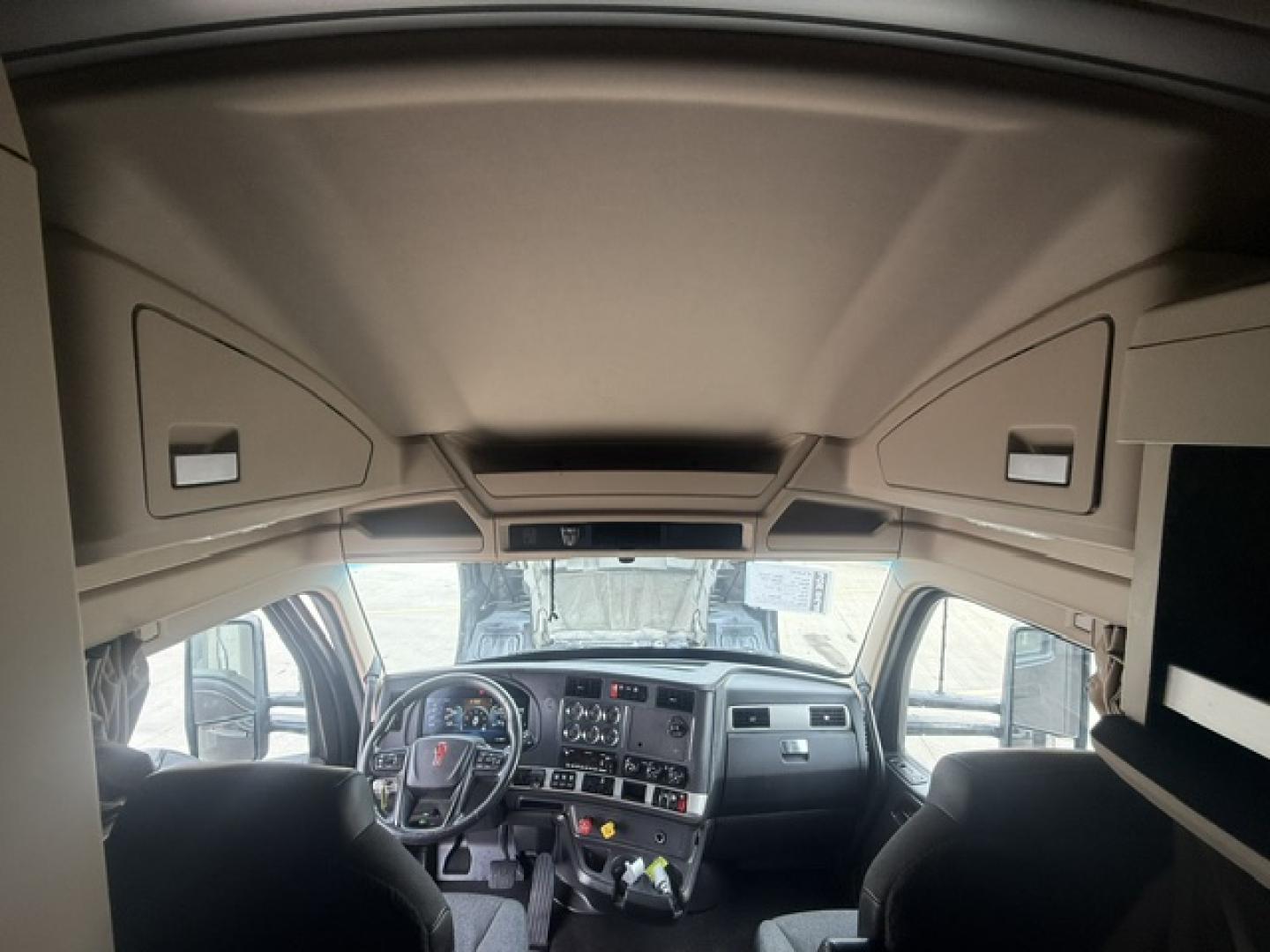 Kenworth T680 truck cabin interior view with steering wheel, dashboard, and overhead storage compartments.